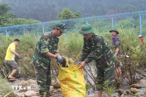 Bộ đội biên phòng cửa khẩu Hoành Mô cùng nhân dân dọn vệ sinh môi trường trên sông biên giới Đồng Mô. (Ảnh: Văn Đức/TTXVN)