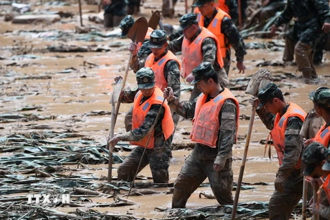 Lực lượng cứu hộ tìm kiếm nạn nhân và khắc phục hậu quả mưa lũ. (Ảnh: THX/TTXVN)