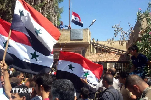 Người dân Syria giương cao quốc kỳ sau khi quân đội giành quyền kiểm soát tỉnh Daraa từ lực lượng nổi dậy ngày 12/7 vừa qua. (Ảnh: AFP/TTXVN)