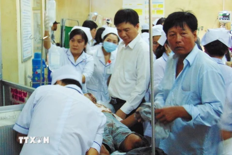 Ông Nguyễn Bình Tân (mặc áo sơmi trắng đứng giữa), Bí thư huyện Vĩnh Lợi đến thăm hỏi nạn nhân đang điều trị tại Bệnh viện Đa khoa Bạc Liêu. (Ảnh: Huỳnh Sử/TTXVN)