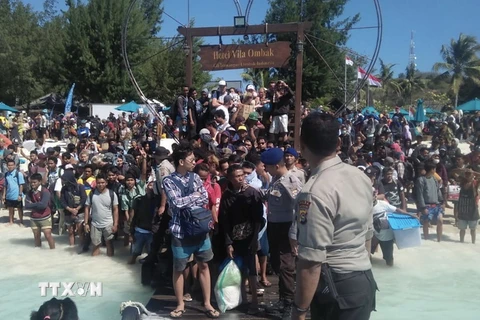 Hàng trăm khách du lịch chờ sơ tán khỏi Gili Trawangan, khu vực lân cận đảo Lombok, Indonesia, ngày 6/8. (Ảnh: AFP/TTXVN)