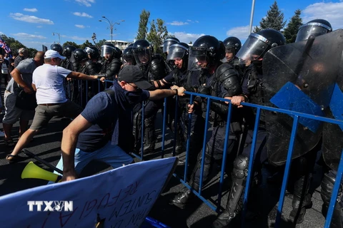 Cảnh sát Romania cố gắng ngăn chặn những người biểu tình quá khích tại Bucharest ngày 10/8. (Ảnh: AFP/TTXVN)
