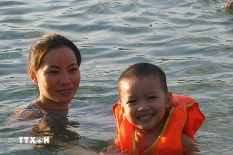 Không chỉ người lớn, trẻ em cũng được mang ra sông tắm vì nắng nóng. (Ảnh: Thanh Hải/TTXVN)