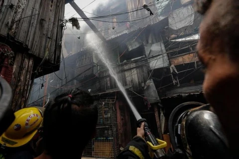 Nhân viên cứu hỏa dập tắt đám cháy còn lại ở Manila, Philippines. (Nguồn: EPA-EFE)