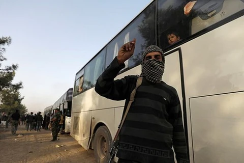 Một tay súng phiến quân trước xe buýt hướng tới tỉnh Idlib của Syria. (Nguồn: Reuters)