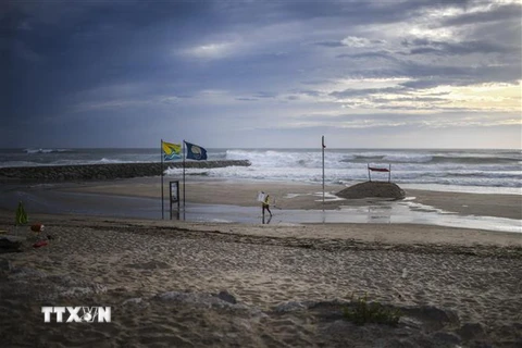 Người dân dỡ bỏ các tấm biển quảng cáo dọc bờ biển tại Costa da Caparica của Bồ Đào Nha trước bão Leslie ngày 13/10. (Ảnh: AFP/TTXVN)
