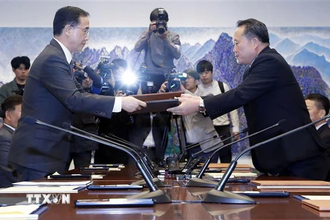Bộ trưởng Thống nhất Hàn Quốc Cho Myoung-gyon (trái) và Chủ tịch Ủy ban Tái thống nhất hòa bình Ri Son-gwon (phải) trao đổi văn kiện sau hội đàm cấp cao liên Triều ở làng đình chiến Panmunjom ngày 15/10. (Ảnh: Yonhap/TTXVN)