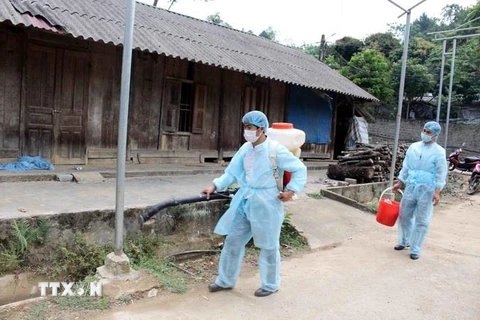 Cơ quan chức năng huyện Tam Đường tiến hành phun thuốc khử trùng, tiêu độc xung quanh gia đình phát hiện dịch bùng phát. (Ảnh: Công Tuyên/TTXVN)