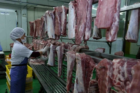 Phân loại thịt lợn đã chế biến và treo trên giá đảm bảo an toàn vệ sinh thực phẩm tại nhà máy. (Ảnh: Vũ Sinh/TTXVN)