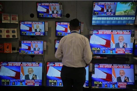 Một nhân viên bán hàng xem Thủ tướng Ấn Độ Narendra Modi phát biểu trên TV ngày 27/3. (Nguồn: Reuters)