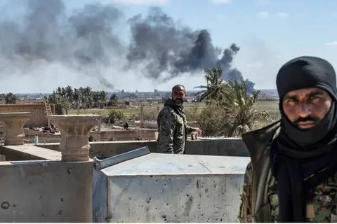 Các thành viên của Lực lượng Dân chủ Syria bảo vệ một tòa nhà trong cuộc pháo kích của IS tại Baghouz.(Nguồn: AFP)