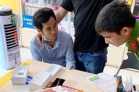 Đối tượng Phạm Ngọc Hậu bị công an bắt giữ khi đang mua hàng trả góp tại một cửa hàng điện thoại di động. (Ảnh: TTXVN)