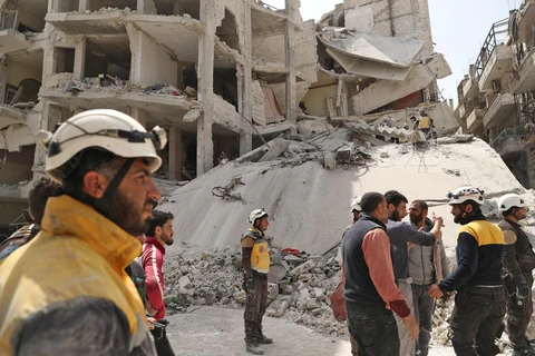 Nhân viên phòng vệ dân sự Syria tìm kiếm các nạn nhân tại khu vực nhà bị sập sau vụ nổ ở Jisr al-Shughur, tỉnh Idlib ngày 24/4. (Ảnh: AFP/TTXVN)