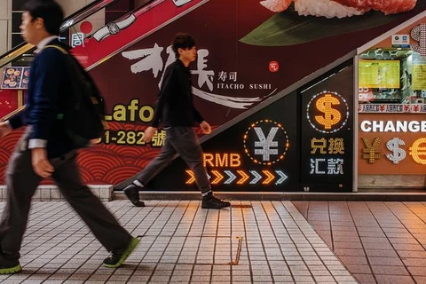 Người đi bộ đi qua một cửa hàng trao đổi tiền tệ ở Hong Kong. (Nguồn: Bloomberg News)