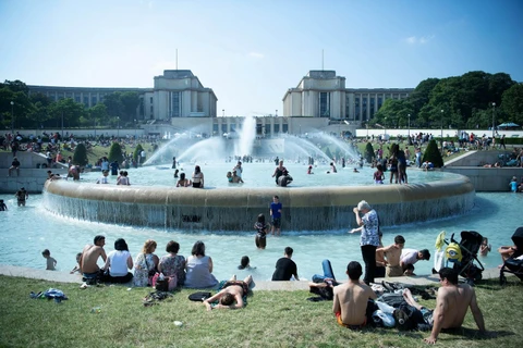 Người dân tránh nắng nóng bên vòi phun nước tại Paris của Pháp, ngày 26/6 vừa qua. (Ảnh: THX/TTXVN)