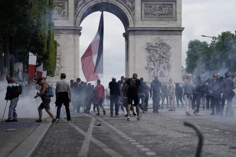 Cảnh sát phun hơi cay để giải tán đám đông người biểu tình quá khích tại đại lộ Champs Elysees ở thủ đô Paris, Pháp, ngày 14/7. (Ảnh: AFP/TTXVN)