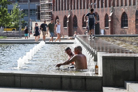 Người dân giải nhiệt tránh nóng tại một đài phun nước ở Berlin, Đức ngày 25/7. (Ảnh: THX/TTXVN)