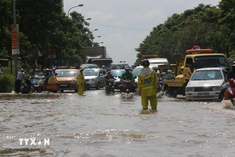 Các phương tiện được lực lượng nhân viên thoát nước Hà Nội chỉ dẫn lưu thông qua đoạn ngập. (Ảnh: Thành Đạt/TTXVN)