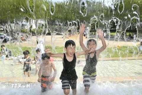 Trẻ em chơi đùa bên vòi phun nước để tránh nắng nóng tại Tokyo, Nhật Bản, ngày 30/7 vừa qua. (Ảnh: Kyodo/TTXVN)
