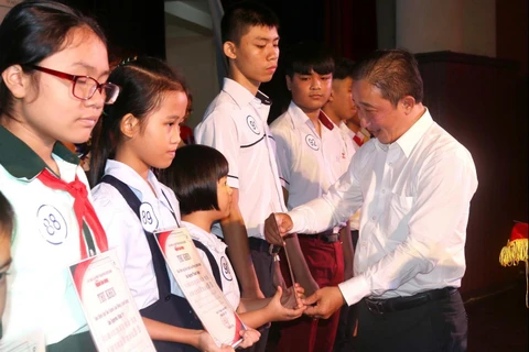 Ông Bùi Thanh Liêm, Phó Tổng Biên tập Báo Người Lao Động trao học bổng cho con em công nhân lao động có hoàn cảnh khó khăn. (Ảnh: Thanh Vũ/TTXVN)