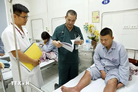Bác sỹ kiểm tra sức khỏe và hội chẩn điều trị cho người bệnh mắc sốt xuất huyết. (Ảnh: Dương Ngọc/TTXVN)