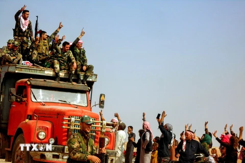 Người dân chào đón các binh sỹ Syria trên tuyến đường cao tốc nối liền hai tỉnh Hassakeh và Aleppo ở Tây Bắc nước này ngày 22/10. (Ảnh: AFP/TTXVN)
