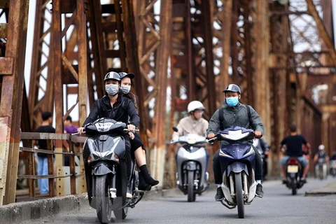 Người dân với trang phục áo ấm đi trên cầu Long Biên (Hà Nội). (Ảnh: Danh Lam/TTXVN)
