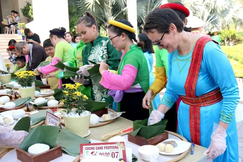 Du khách quốc tế hào hứng gói bánh chưng và trải nghiệm không gian Tết Việt. (Ảnh: Nguyễn Thanh/TTXVN)