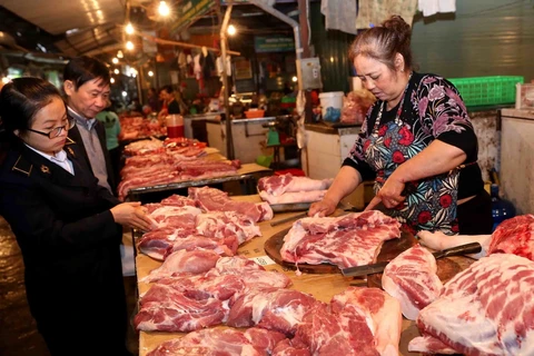 Nhân viên Thú y phối hợp với Ban Quản lý chợ đầu mối Nam Hà Nội kiểm tra sản phẩm thịt lợn tại quầy hàng tại chợ. (Ảnh: Vũ Sinh/TTXVN)