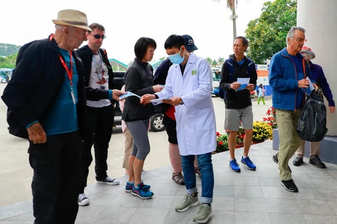  Cán bộ nhân viên Trung tâm Kiểm soát bệnh tật phát tờ rơi truyền thông về nCov cho khách du lịch đến thăm quan vịnh Hạ Long tại bến tầu du lịch Tuần Châu-Hạ Long. (Ảnh: TTXVN phát) 