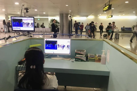 Nhân viên sân bay kiểm tra màn hình hiển thị máy quét thân nhiệt đối với hành khách quốc tế đến Việt Nam. (Ảnh: Đinh Hằng/TTXVN)