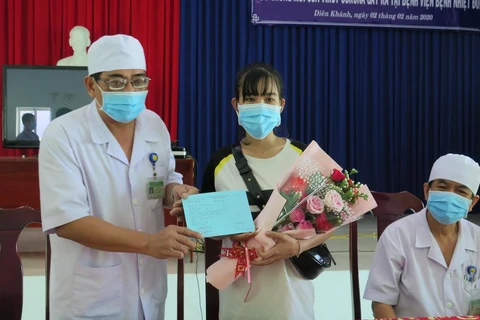 Phó Giám đốc Bệnh viện Bệnh Nhiệt đới Khánh Hòa Nguyễn Vũ Quốc Bình tặng hoa và trao giấy xuất viện cho bệnh nhân Lê Thị Thu H. (Ảnh: Phan Sáu/TTXVN)