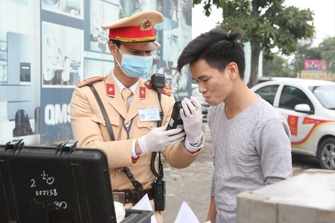 Cảnh sát giao thông Hà Nội sử dụng phương tiện an toàn kiểm tra nồng độ cồn trong khí thở đối với người tham gia giao thông. (Ảnh: Doãn Tấn/TTXVN)