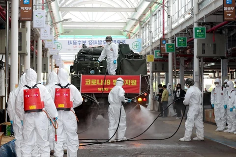 Binh sỹ phun thuốc khử trùng tại một khu chợ ở Jeju, Hàn Quốc, nhằm ngăn chặn sự lây lan của COVID-19 ngày 11/3. (Ảnh: THX/TTXVN)