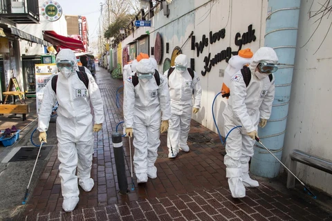 Binh sỹ Hàn Quốc mặc trang phục bảo hộ phun khử trùng một tuyến phố ở thành phố Daegu ngày 5/3 vừa qua. (Ảnh: THX/TTXVN)