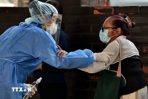 Y tá giúp đỡ một bệnh nhân lớn tuổi tới khám bệnh tại Tegucigalpa, Honduras, ngày 1/4 vừa qua. (Ảnh: AFP/TTXVN)