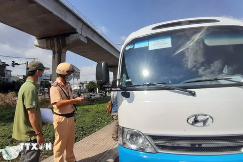Lực lượng liên ngành kiểm tra phương tiện đưa rước nhân viên trên xa lộ Hà Nội. (Ảnh: Tiến Lực/TTXVN)
