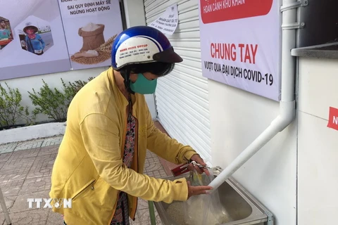 Một người phụ nữ bán vé số nhận gạo. (Ảnh minh họa: Hứa Chung/TTXVN)