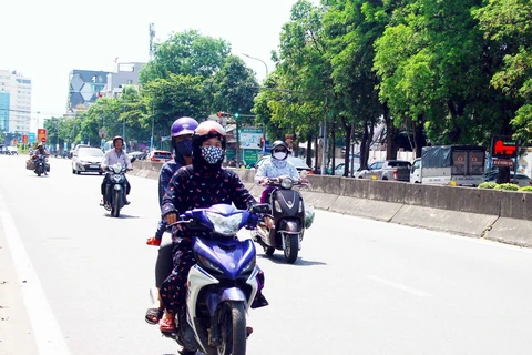 Người dân đều trang bị khẩu trang và mặc áo chống nắng kín khi di chuyển trên đường trong thời tiết nắng nóng. (Ảnh: Tá Chuyên/TTXVN)