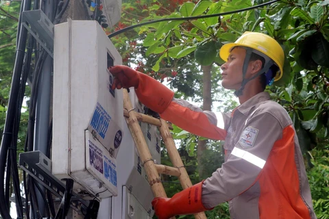 Công nhân Điện lực kiểm tra đồng hồ đo điện của các hộ dân. (Ảnh: Văn Đạt/TTXVN)