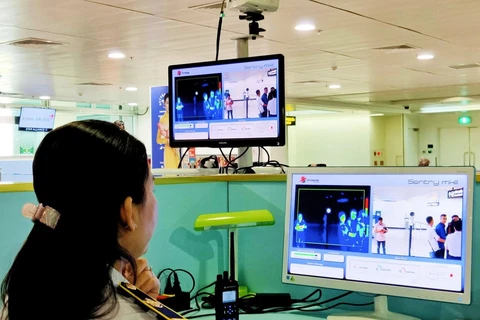 Nhân viên Trung tâm Kiểm dịch y tế quốc tế giám sát thân nhiệt của hành khách nhập cảnh tại sân bay Tân Sơn Nhất Thành phố Hồ Chí Minh. (Ảnh: TTXVN phát)