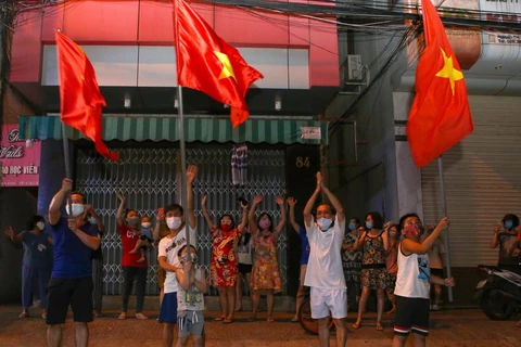 Người dân ở trên tuyến đường Nguyễn Thị Minh Khai vui mừng sau khi hoàn thành cách ly 14 ngày trong khu vực phong tỏa. (Ảnh: Trần Lê Lâm/TTXVN)