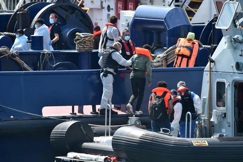 Lực lượng bảo vệ biên giới Anh đưa người di cư vượt biển từ Pháp qua Eo biển Manche, tới cảng Dover ở bờ biển đông nam nước Anh ngày 9/8 vừa qua. (Ảnh: AFP/TTXVN)