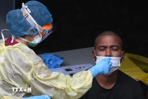 Nhân viên y tế lấy mẫu dịch xét nghiệm COVID-19 cho người dân tại Singapore. (Ảnh: AFP/TTXVN)
