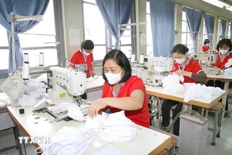 Công nhân sản xuất khẩu trang vải dệt kim kháng khuẩn. (Ảnh: Phương Hoa/TTXVN)