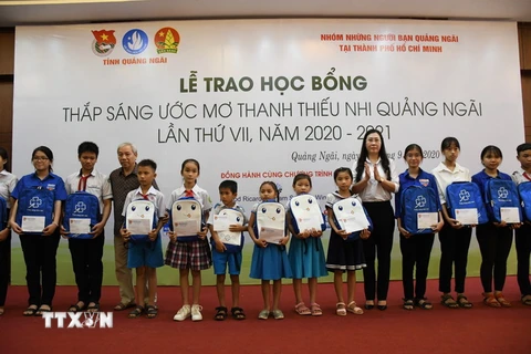 Đại diện Nhóm những người bạn Quảng Ngãi tại TP Hồ Chí Minh và lãnh đạo tỉnh Quảng Ngãi trao học bổng cho các em học sinh. (Ảnh: Đinh Hương/TTXVN)