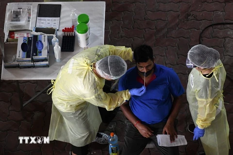 Nhân viên y tế lấy mẫu dịch xét nghiệm COVID-19 cho người lao động tại Singapore. (Ảnh: AFP/TTXVN)