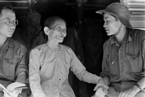 Phóng viên Thanh Phong của TTXGP tại Quảng Trị (bên phải) nói chuyện với một gia đình nuôi cán bộ cách mạng tại thị xã Quảng Trị năm 1968. (Ảnh: TTXVN) 