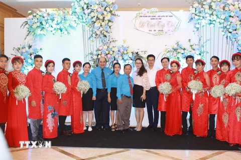 Ông Hồ Xuân Lâm, Phó Chủ tịch Liên đoàn Lao động TP Hồ Chí Minh với các đại biểu cùng các cô dâu, chú rể tại lễ cưới tập thể. (Ảnh: Thanh Vũ/TTXVN)