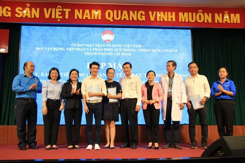 Đại diện Ủy ban Mặt trận Tổ quốc Việt Nam Thành phố Hồ Chí Minh, đại diện nhân viên y tế cùng đại diện các nhà tài trợ chụp ảnh lưu niệm. (Ảnh: Đinh Hằng/TTXVN)